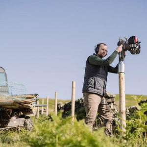 Farmer installing a fence along a crumbling wall, next to his ATV, using Easy Petrol Post Driver with Mutli UKA to drive in the posts