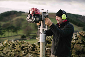 Contractor installing a 90mm post along a farm wall, using the Easy Petrol Post Driver